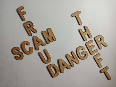 Fraud scam danger theft cross word business terminology presented on white background with wooden alphabetic letters.の写真素材