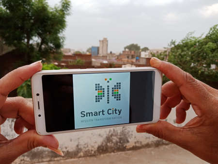 District Katni, Madhya Pradesh, India - 23 May 2020: Smart city government scheme displayed on smart phone screen by indian woman at open background.のeditorial素材