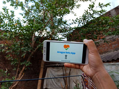 DISTRICT KATNI, INDIA - 28 MAY 2020: An indian lady holding smart phone with displaying aarogya setu...