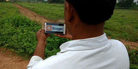 DISTRICT KATNI, INDIA - SEPTEMBER 18, 2019: Blogger logo displayed on smart phone screen by indian village man hand holding mobile concept.のeditorial素材