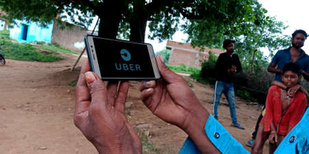 DISTRICT KATNI, INDIA - SEPTEMBER 18, 2019: Uber Technologies Inc Ride sharing company logo displayed on smart phone screen by indian village man hand holding mobile concept.のeditorial素材