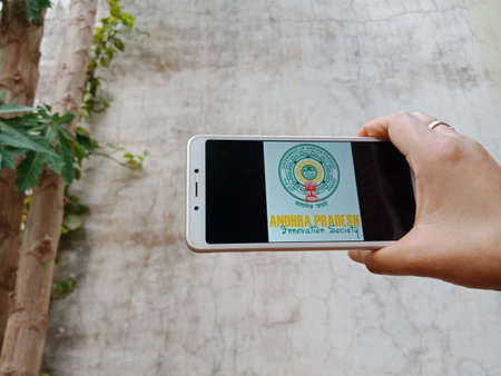 DISTRICT KATNI, INDIA - 28 MAY 2020: An indian lady holding smart phone with displaying andhra pradesh innovation society symbol on screen, modern education concept for village people.のeditorial素材