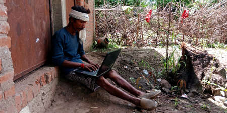 DISTRICT KATNI, INDIA - AUGUST 20, 2019: An indian village farmer man operating laptop, concept for...