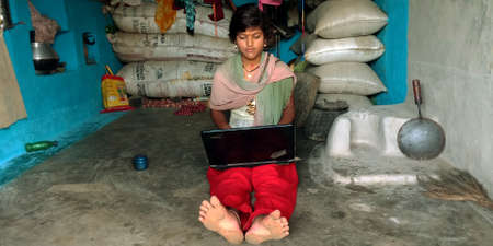 DISTRICT KATNI, INDIA - AUGUST 14, 2019: An indian village young girl operating laptop around poor and dirty place at home.のeditorial素材