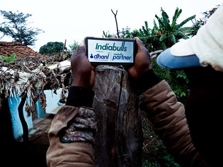 DISTRICT KATNI, INDIA - DECEMBER 20, 2019: Indiabulls Conglomerate dhani instant loan logo presented on smart phone digital screen by indian village people hand holding mobile concept for digital education.のeditorial素材