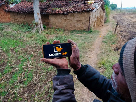 DISTRICT KATNI, INDIA - DECEMBER 20, 2019: Money Tap instant loan online portal presented on smart phone digital screen by indian village people hand holding mobile concept.のeditorial素材