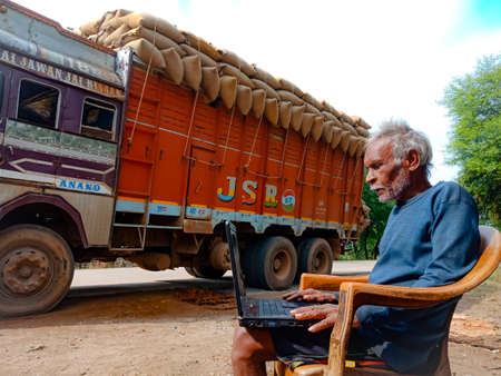 DISTRICT KATNI, INDIA - JANUARY 01, 2020: An indian elderly poor man operating laptop computer...