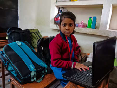 DISTRICT KATNI, INDIA - JANUARY 13, 2020: Indian primary school girl student operating laptop technology at class Benches.のeditorial素材