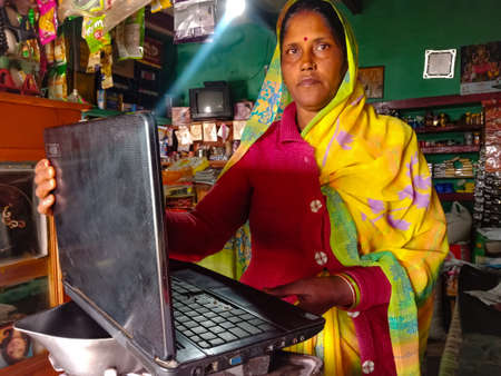 DISTRICT KATNI, INDIA - JANUARY 01, 2020: An indian shopkeeper woman operating laptop technology at...