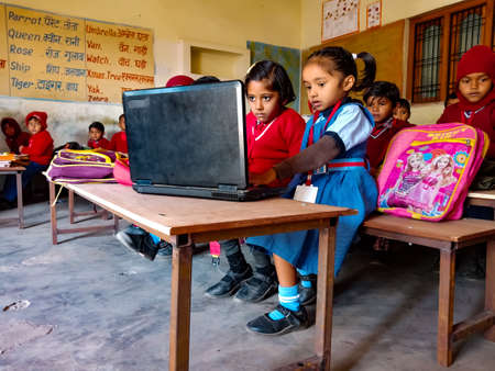 DISTRICT KATNI, INDIA - JANUARY 13, 2020: Indian primary school kids learning together about laptop technology at class Benches.のeditorial素材