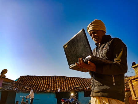 DISTRICT KATNI, INDIA - JANUARY 25, 2020: An indian matured farmer learning alone about laptop at...