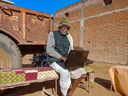 DISTRICT KATNI, INDIA - JANUARY 25, 2020: An indian old man working on laptop while sitting at...