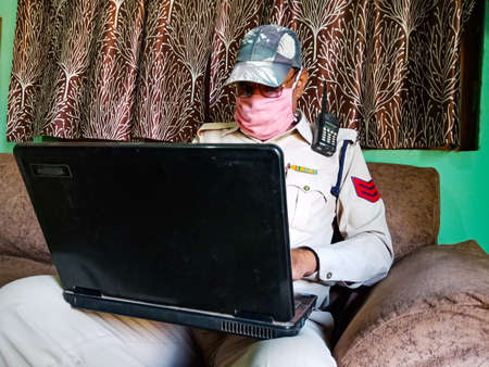 DISTRICT KATNI, INDIA - MAY 21, 2020: An indian girl calling on mobile phone at home wearing face mask for coronavirus protection at home.のeditorial素材