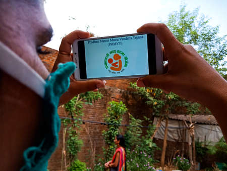 DISTRICT KATNI, INDIA - MAY 28, 2020: pradhan mantri matru vandana yojana in hindi, Indian Government scheme for country people presented on mobile screen by asian lady.のeditorial素材