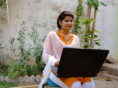DISTRICT KATNI, INDIA - MAY 16, 2020: An indian corporate girl looking at camera during laptop working at garden.のeditorial素材