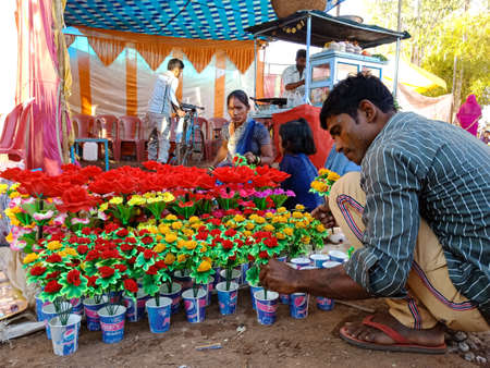 DISTRICT KATNI, INDIA - FEBRUARY 02, 2020: Indian village man arranging artificial flowers pot at street poor market during hindu traditional festival summer season fest program.のeditorial素材