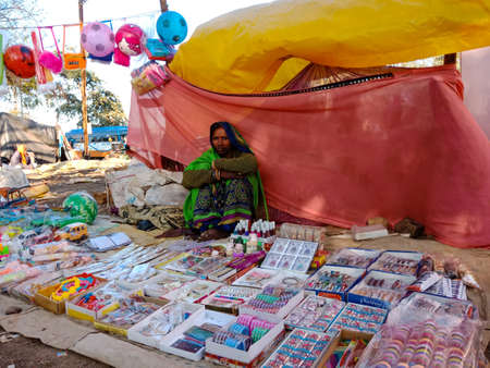 DISTRICT KATNI, INDIA - FEBRUARY 02, 2020: Indian village poor lady selling toys at street poor market during hindu traditional festival summer season.のeditorial素材