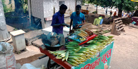 DISTRICT JABALPUR, INDIA - AUGUST 17, 2019: Asian shopkeeper selling sweet corn for tourist at Narmada river street market.のeditorial素材