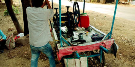 DISTRICT KATNI, INDIA - JULY 16, 2019: An indian village man operation sugarcane grinding machine on...