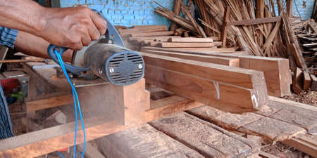DISTRICT KATNI, INDIA - SEPTEMBER 16, 2019: Asian wooden worker finishing wood logs from electric machine at Saw mill factory site.のeditorial素材