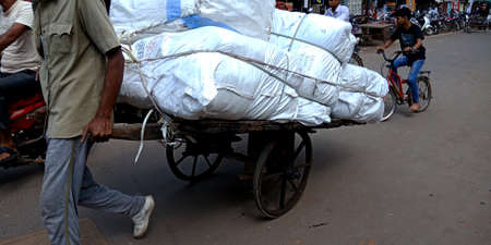 DISTRICT KATNI, INDIA - OCTOBER 05, 2019: An indian transportation worker pulling loaded rickshaw on...
