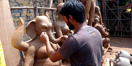 DISTRICT KATNI, INDIA - SEPTEMBER 07, 2019: Indian statue maker creating traditional ganesha amazing soil art at craft item workshop.のeditorial素材