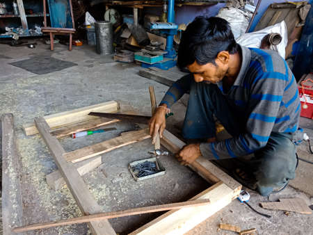 DISTRICT KATNI, INDIA - DECEMBER 09, 2019: An indian mechanic making trucks body frame from wooden...