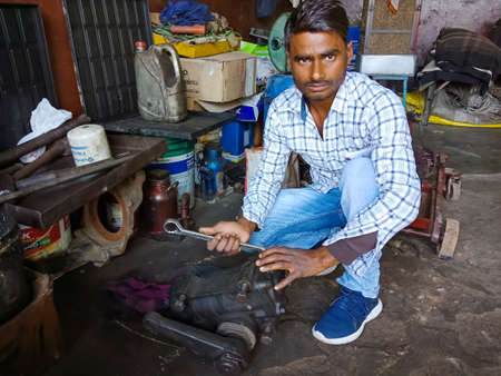 DISTRICT KATNI, INDIA - DECEMBER 09, 2019: An indian mechanic repairing engine from screw driver at...