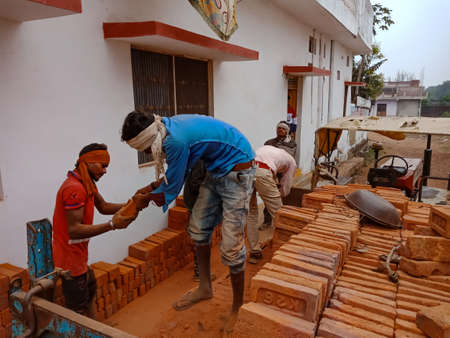 DISTRICT KATNI, INDIA - DECEMBER 21, 2019: Indian village worker unloading bricks from loaded...