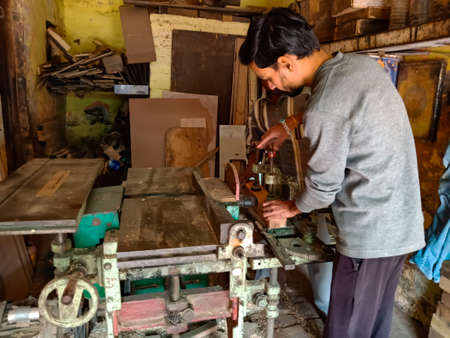 DISTRICT KATNI, INDIA - JANUARY 08, 2020: An indian woodworker adjusting machine handle for chopping...