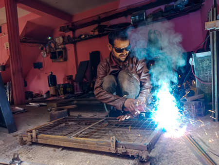 DISTRICT KATNI, INDIA - JANUARY 08, 2020: An indian village blacksmith welding on steel structure.