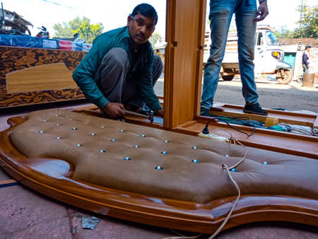 DISTRICT KATNI, INDIA - JANUARY 08, 2020: An indian wooden artist making double bed on furniture...