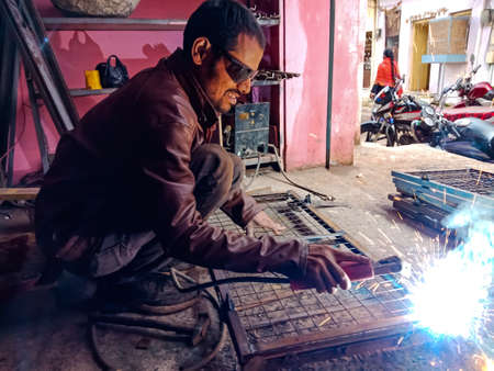 DISTRICT KATNI, INDIA - JANUARY 08, 2020: An indian blacksmith welding on steel structure.