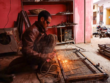 DISTRICT KATNI, INDIA - JANUARY 08, 2020: An asian village blacksmith man welding on steel...