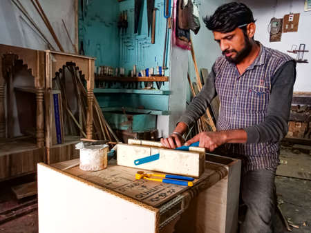 DISTRICT KATNI, INDIA - JANUARY 08, 2020: An indian wooden artist cutting wood log from blade at workshop.のeditorial素材