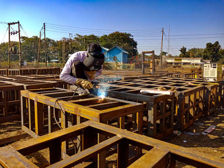 DISTRICT KATNI, INDIA - JANUARY 17, 2020: Asian maintenance worker welding on iron net during railway bridge construction works.のeditorial素材