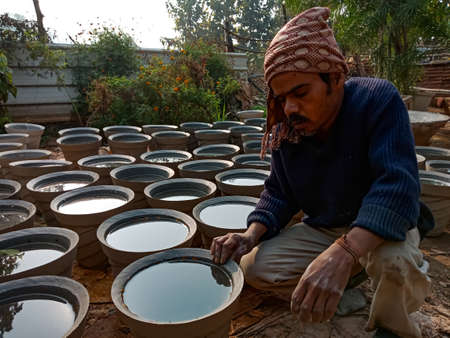 DISTRICT KATNI, INDIA - JANUARY 18, 2020: An indian artist sitting with constructed cement pot on...