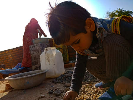DISTRICT KATNI, INDIA - JANUARY 13, 2020: An indian male kid sitting at construction site at sky background.のeditorial素材