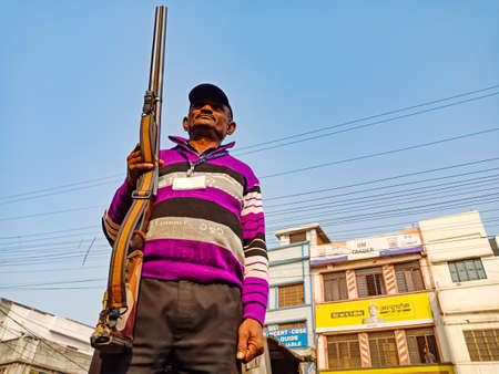 DISTRICT KATNI, INDIA - JANUARY 18, 2020: An indian security guard holded rifle gun on blue sky...