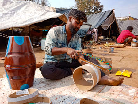 DISTRICT KATNI, INDIA - JANUARY 21, 2020: Indian poor villager artist cutting musical drum base from...