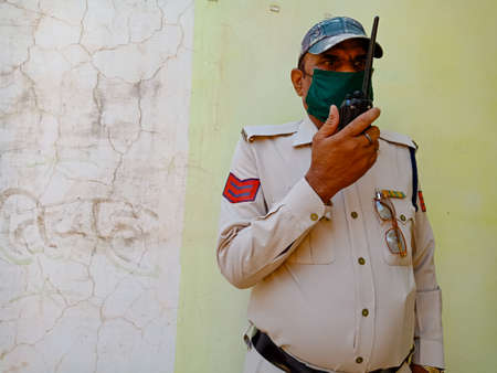 DISTRICT KATNI, INDIA - MAY 21, 2020: An asian police officer talking on wireless walkie talkie...