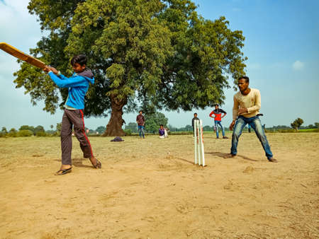 DISTRICT KATNI, INDIA - JANUARY 01, 2020: Asian poor village boys playing cricket game at countryside rural environment.のeditorial素材
