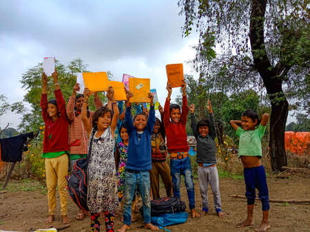 DISTRICT KATNI, INDIA - JANUARY 01, 2020: Indian government school poor children showing excitement with books together at village area outdoor environment.のeditorial素材