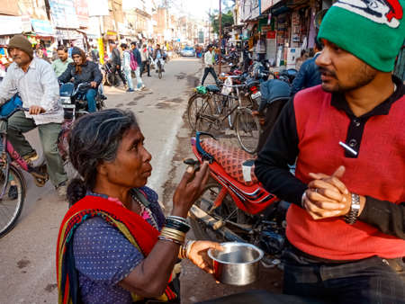 DISTRICT KATNI, INDIA - JANUARY 10, 2020: An indian poor woman begging money from man on road.のeditorial素材