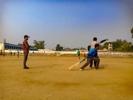 DISTRICT KATNI, INDIA - DECEMBER 02, 2019: Indian city people playing cricket together at forester playground around beautiful sky field.のeditorial素材