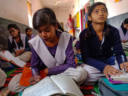 DISTRICT KATNI, INDIA - JANUARY 21, 2020: Indian government school female student writing on notebook at classroom.のeditorial素材