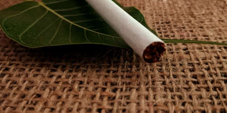 Single leaf surface cigarette on brown sack mat background, pack of cigarettes, close-up of a cigaretteの写真素材