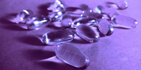 Transparent medicine liquid capsule presented on purple background.