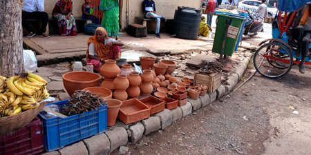 DISTRICT KATNI, INDIA - AUGUST 15, 2019: An indian village poor old woman selling soil pot on street market.のeditorial素材