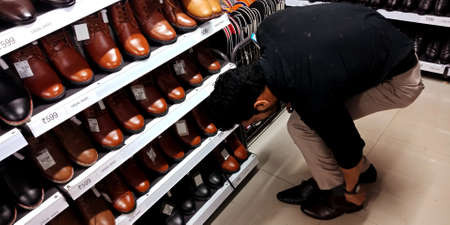 DISTRICT KATNI, INDIA - SEPTEMBER 16, 2019: An indian man trying Branded shoes on hand for buying at mega mart store.のeditorial素材